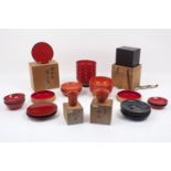 Two red lacquer sake cups of ribbed spiral form with black lacquer bases, 6.1cm and 4.8cm diameters,