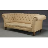 A Victorian button back Chesterfield sofa, upholstered in cream fabric, raised on turned mahogany