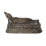 A Burmese bronze figure of Buddha, 19th century, reclining with head resting on right hand, on lotus
