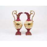 A pair of ceramic wine ewers of red and cream ground, with gilt decorative highlights of leafy