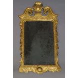 A George I gilt wall mirror, with swan neck pediment, flanking carved cartouche, the bevelled plate,