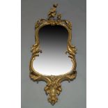 A gilt wood Rococo taste wall mirror, late 18th, early 19th Century, of waisted form, with carved