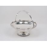 A silver swing handled cake basket, Sheffield, c.1934, Walker & Hall, the plain bowl raised on a