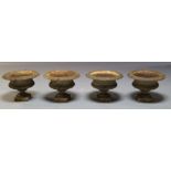 Four cast iron garden urns, 20th Century, with flared rims on lobed plinth bases, each 27cm high,