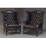 A pair of brown leather wing back armchairs, late 20th Century, with button backs and brass stud
