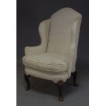 A George II style wingback armchair, with earlier elements, the shaped back and scrolling arms,