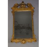 A George I gilt wall mirror, with swan neck pediment, flanking carved cartouche,the bevelled