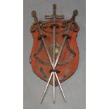 A wall mounted panoply, 17th century style, of shield form, 69cm long, the red body with applied
