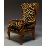 A French walnut wing armchair, 19th Century, upholstered in tiger print fabric with brass stud