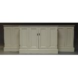 A white painted breakfront low cabinet, late 20th Century, with four panelled folding doors,