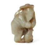 A Chinese celadon jade fisherman, early 20th century, carved as a fisherman loading his fishing