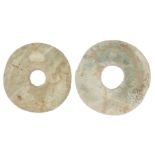 Two Chinese archaistic green hardstone bi, each partially calcified, 13cm and 12cm diameter