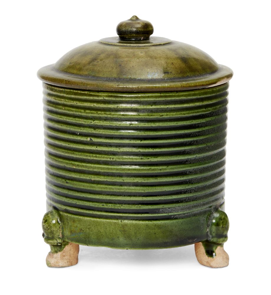 A rare Chinese green-glazed pottery tripod jar and cover, Tang dynasty, the cylindrical ribbed