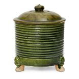 A rare Chinese green-glazed pottery tripod jar and cover, Tang dynasty, the cylindrical ribbed