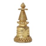 A Tibetan gilt bronze jewelled stupa, 15th/16th century, the bell-formed base rising from a lotus