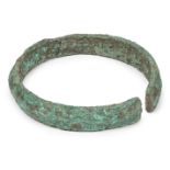 A Chinese bronze neck ring, Neolithic period, with central ridge, heavily encrusted, 13cm diameter