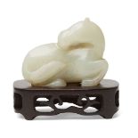 A Chinese pale green jade horse, late 19th century, carved in recumbent pose with head turned