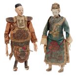 Two Chinese dolls, late 19th century, with painted wood heads and limbs, one wearing a coral