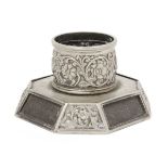An octagonal based white metal inkwell, both the base and the well richly decorated with repousse