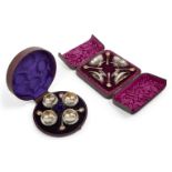 Two cased Victorian silver condiment sets, comprising a set of four rounded salt cellars, London,