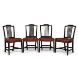 A set of four George III mahogany dining chairs, the shaped crest rails with carved rosettes above