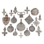 A collection of Ethiopian white metal cross form pendants of varying sizes and designs, to include a