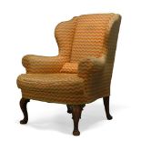 A George III style wingback armchair, first half 20th Century, with serpentine wings, upholstered in