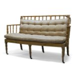A Regency faux bamboo and cream painted settee, the slatted faux bamboo backrest and arms, with