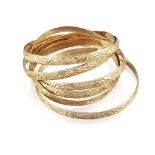 Six bangles, of matching hoop design with scroll decoration, one splitall stamped 18ct, total weight