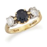 An 18ct gold, sapphire and diamond three stone ring, the oval sapphire between brilliant-cut