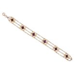 A late 19th century gold, garnet and seed pearl bracelet, composed of a series of openwork scrolling