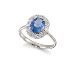 An 18ct. gold, sapphire and diamond cluster ring, the single oval mixed-cut sapphire in 18ct.