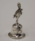 A silver bell with stork formed finial