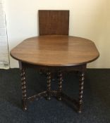 An early 20th century carved oak barley twist two leaf extending dining table