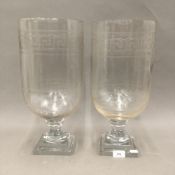 A pair of glass hurricane lamps. 42 cm high.