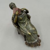 A cold painted bronze model of a seated girl,