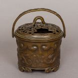 A Chinese patinated bronze censer Of cylindrical form, with loop handle and pierced top,