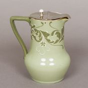 A Moorcroft Macintyre Esso faience jug The green glazed body with scrolling floral decoration.