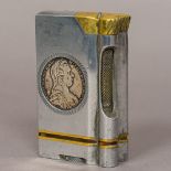 A large brass and steel table lighter Inset to either side with a silver coin. 10.5 cm high.