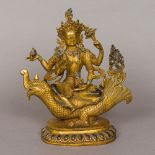 An Eastern gilt bronze model of a four-armed deity Modelled seated on a dragon,