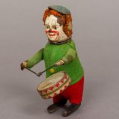 A Schuco tin plate clockwork drumming clown With felt clothing and painted detail. 11.5 cm high.