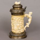 A 19th century unmarked silver mounted carved ivory stein The hinged embossed lid set with a