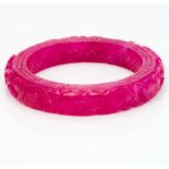 A Chinese ruby coloured jade bangle With all over scrolling carved decoration. 8 cm diameter.