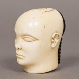 A 19th century Chinese carved ivory head Of male form with black stained plaited hair. 5 cm high.
