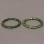 Two Chinese spinach jade bangles Each of plain tubular form. Each approximately 8 cm diameter.
