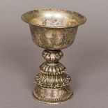 A Tibetan unmarked silver stem cup The engraved flared bowl above the central pierced knop,