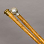 Two walking canes One set with a silver knop finial, the other with a brass finial.
