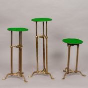 Three late 19th/early 20th century adjustable shop display stands Each of tubular brass form,