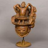 A carved wooden tribal Gelede dance mask/headdress Depicting four tribesmen standing on a snake and