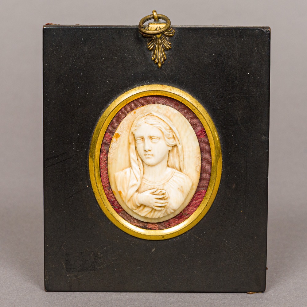 A 19th century carved ivory panel Of oval form, carved as the Virgin Mary,